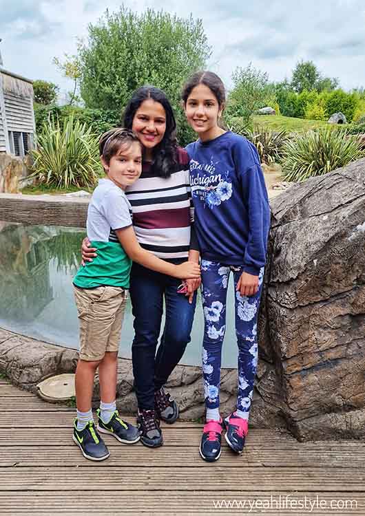 A Woman and two children standing near the penguin viewing area