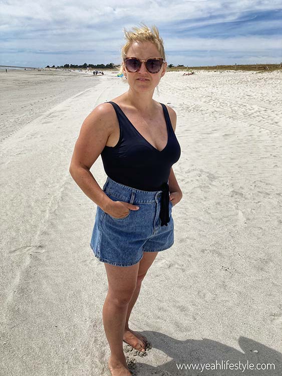 Woman wearing black top with shorts on beach